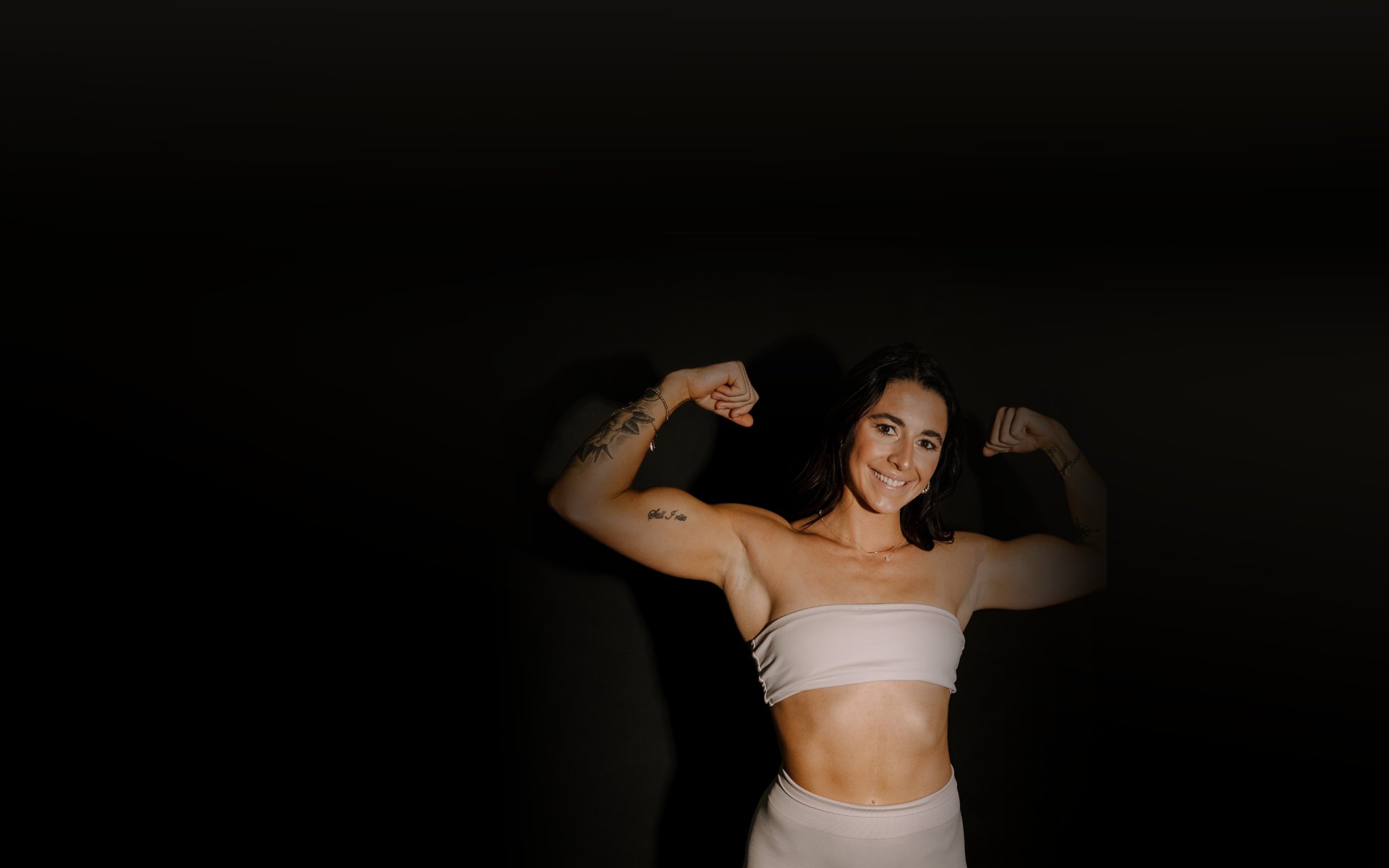 Mallory smiling and flexing in a studio portrait
